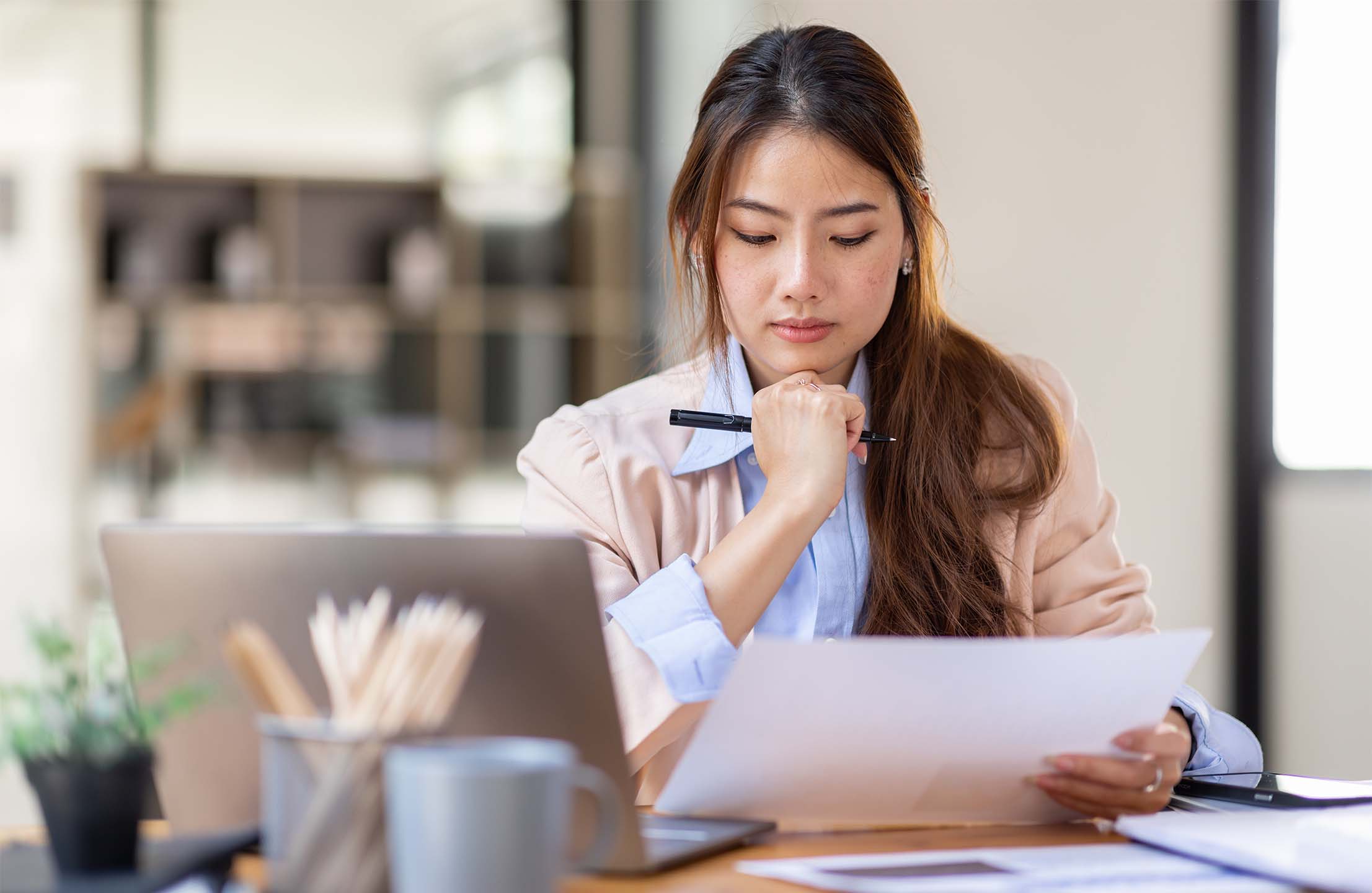 Person reviewing notes while planning instructional design content at a laptop