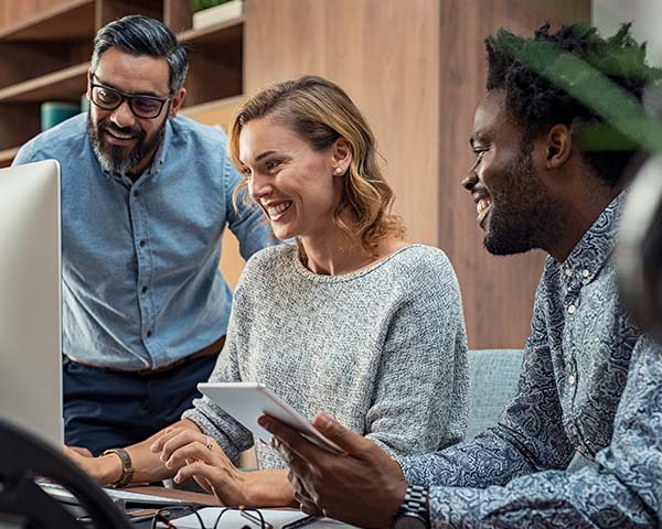 Team working together on a laptop while discussing online training